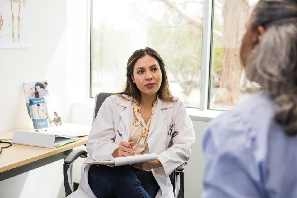 The female healthcare professional listens to her patient give some clarification about her medical history so she can make notes.